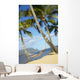 Hammock tied between palm trees on sandy beach Wall Mural