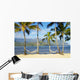 Two hammocks hanging between palm trees on sandy tropical beach Wall Mural