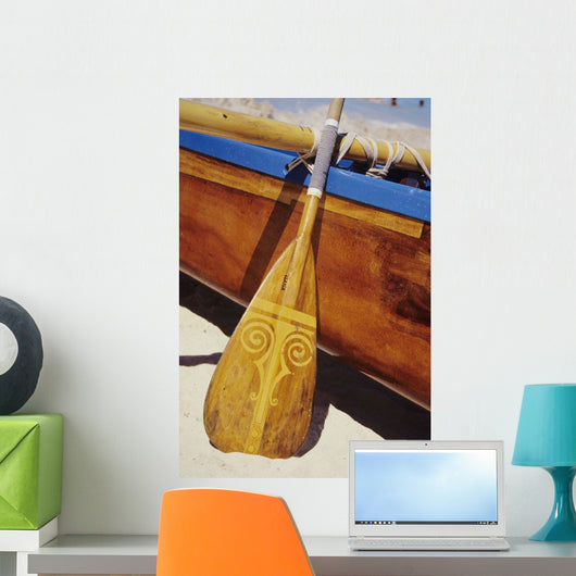 Wooden paddle and outrigger canoe on beach Wall Mural