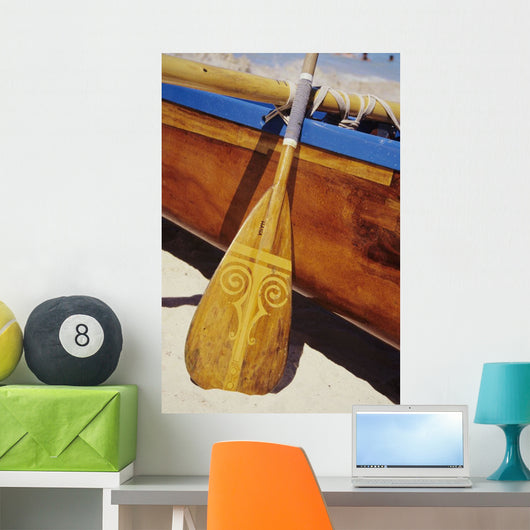 Wooden paddle and outrigger canoe on beach Wall Mural