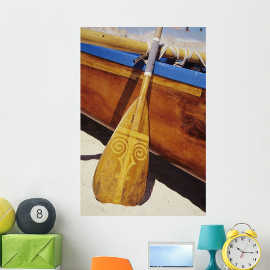 Wooden paddle and outrigger canoe on beach Wall Mural