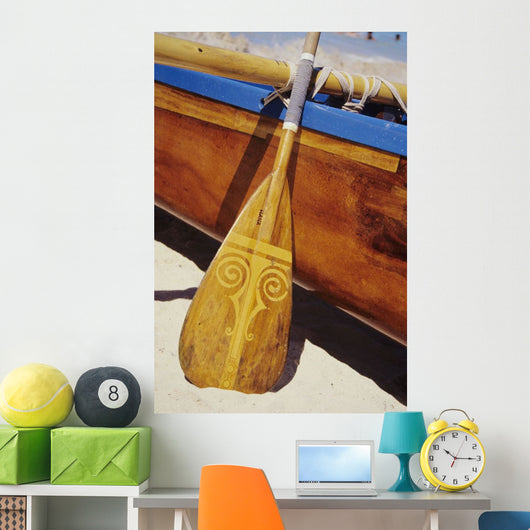 Wooden paddle and outrigger canoe on beach Wall Mural