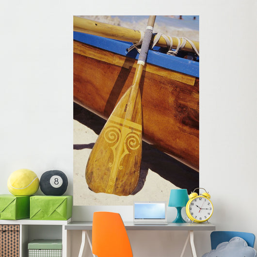 Wooden paddle and outrigger canoe on beach Wall Mural
