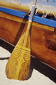 Wooden paddle and outrigger canoe on beach Wall Mural
