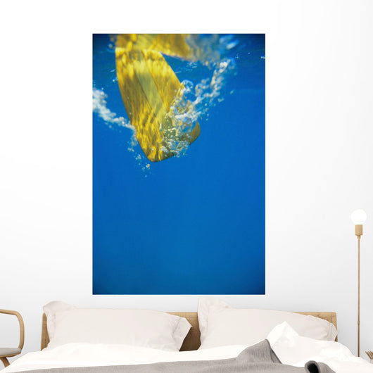 Underwater View Of Yellow Paddle Stroking Water, Creating Bubbles Wall Mural