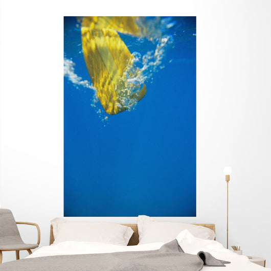 Underwater View Of Yellow Paddle Stroking Water, Creating Bubbles Wall Mural