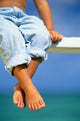 Hawaii, Legs And Feet Of Young Boy Sitting On A Bench By The Ocean Wall Mural