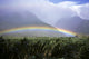 View Of Low Rainbow At Base Of Mountains, Clouds, Blue Sky, Field Wall Mural