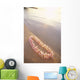 Pale Pink Plumeria Lei Along Shoreline Of Calm Water Wall Mural