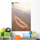 Pale Pink Plumeria Lei Along Shoreline Of Calm Water Wall Mural