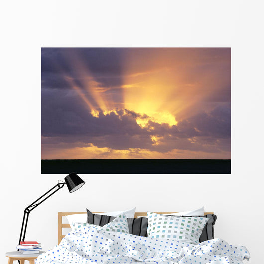 Sunrays Stream Out From Behind Clouds At Sunset, Over Dark Ocean Wall Mural