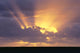 Sunrays Stream Out From Behind Clouds At Sunset, Over Dark Ocean Wall Mural