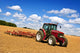 Tractor in plowed field Wall Mural