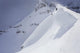 Skier On Crest Of Big Drop, Dwarfed By Mountain Wall Mural