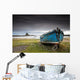 A Weathered Boat Sitting On The Shore With Lindisfarne Castle Wall Mural