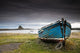 A Weathered Boat Sitting On The Shore With Lindisfarne Castle Wall Mural