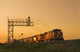 Locomotives Pulling Rail Hopper Cars Pass An Overhead Rail Signal Wall Mural