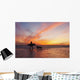 A Surfer Walks In Shallow Water With Her Dog At Sunset Wall Mural