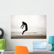 An Individual Wearing A Wet Suit Jumping In Mid-Air On A Beach Wall Mural