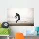 An Individual Wearing A Wet Suit Jumping In Mid-Air On A Beach Wall Mural