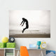 An Individual Wearing A Wet Suit Jumping In Mid-Air On A Beach Wall Mural