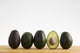 A Row Of Avocados Standing Upright On A Wooden Board With One Cut Wall Mural