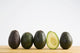 A Row Of Avocados Standing Upright On A Wooden Board With One Cut Wall Mural