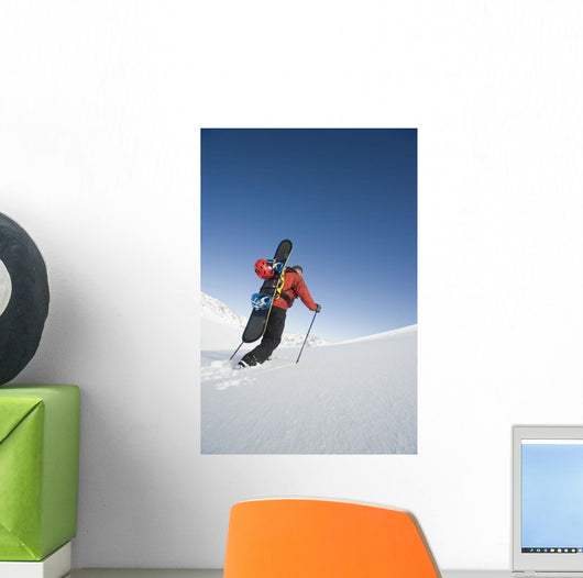 Man Backcountry Snowshoeing While Carrying A Snowboard Wall Mural