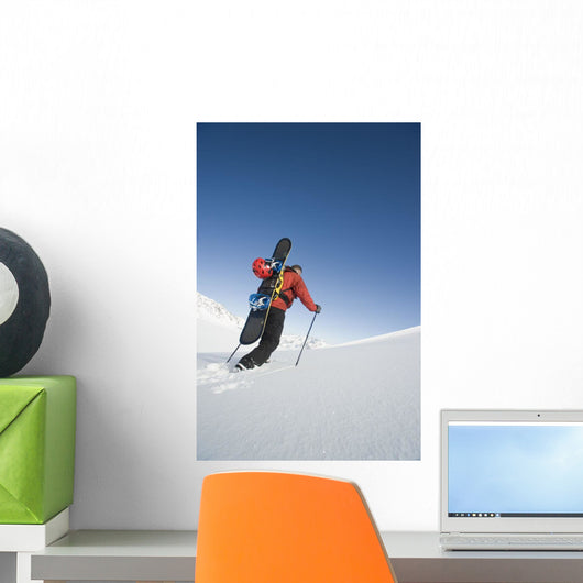 Man Backcountry Snowshoeing While Carrying A Snowboard Wall Mural