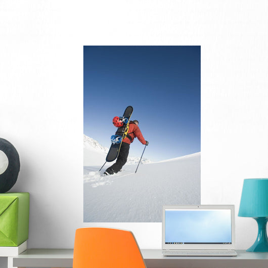 Man Backcountry Snowshoeing While Carrying A Snowboard Wall Mural