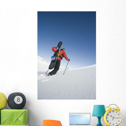 Man Backcountry Snowshoeing While Carrying A Snowboard Wall Mural