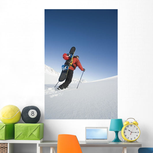 Man Backcountry Snowshoeing While Carrying A Snowboard Wall Mural