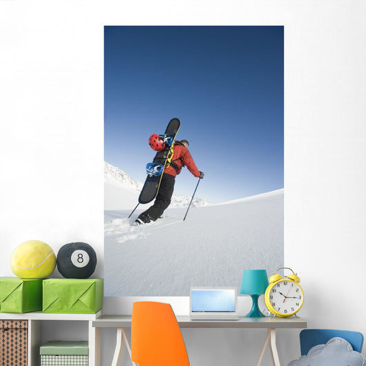 Man Backcountry Snowshoeing While Carrying A Snowboard Wall Mural