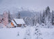 Snowcovered Home In A Wintry Meadow At Dawn With Inside Lights On Wall Mural