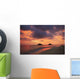Vibrant sunset with a couple embracing on beach Wall Mural