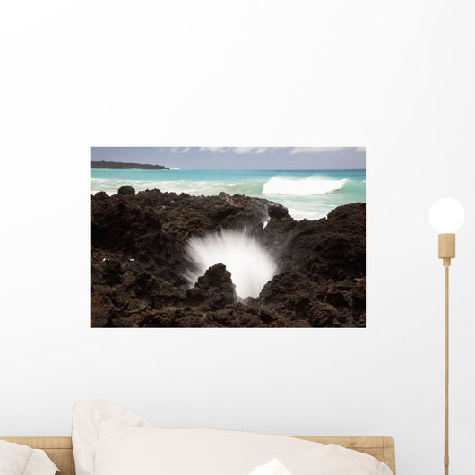 A burst of water through a blowhole in some lava rocks Wall Mural