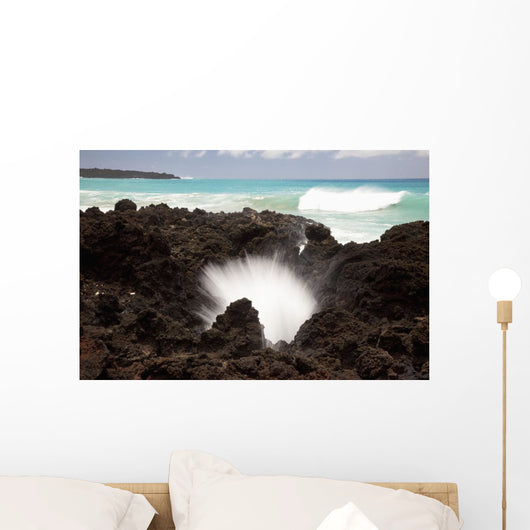 A burst of water through a blowhole in some lava rocks Wall Mural