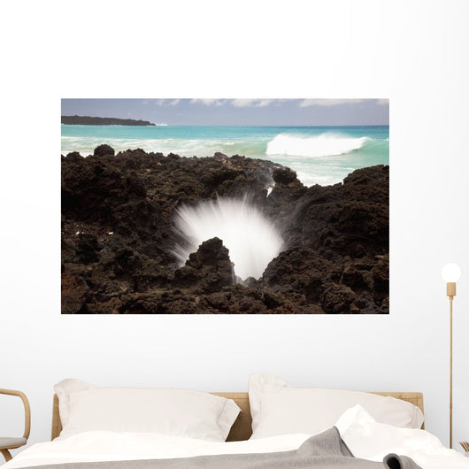 A burst of water through a blowhole in some lava rocks Wall Mural