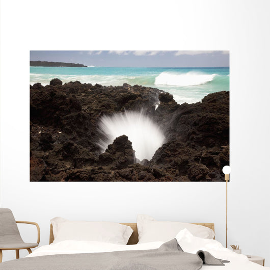 A burst of water through a blowhole in some lava rocks Wall Mural