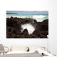 A burst of water through a blowhole in some lava rocks Wall Mural