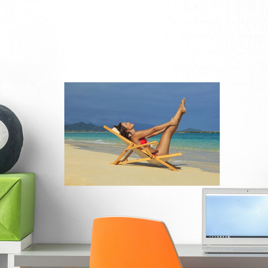 Beautiful woman stretches in a lounge chair on the beach Wall Mural