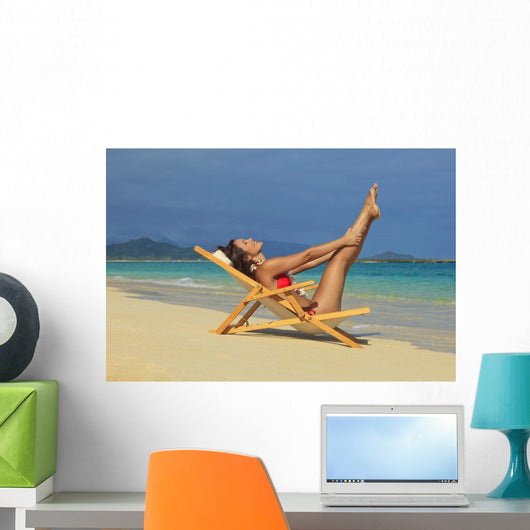 Beautiful woman stretches in a lounge chair on the beach Wall Mural