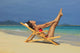 Beautiful woman stretches in a lounge chair on the beach Wall Mural