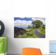 A stone wall lines a country road with views of Maui in the background Wall Mural