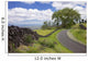 A stone wall lines a country road with views of Maui in the background Wall Mural