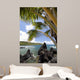 Sunny blue skies light up the lush coast with palm trees Wall Mural