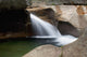 A forest riverbed and waterfall Wall Mural