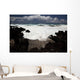 A wave breaks with lave rocks in the foreground Wall Mural