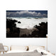 A wave breaks with lave rocks in the foreground Wall Mural