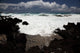 A wave breaks with lave rocks in the foreground Wall Mural